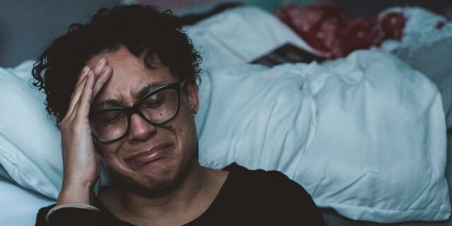 Huiselijk geweld vrouw huilt machteloos naast het bed